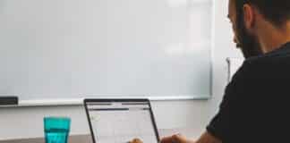 man sitting at the table while using laptop computer