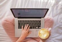 person using MacBook Pro and holding cappuccino